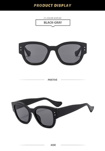 Detail view of black chunky sunglasses with grey lenses and stylish metal rivet accents