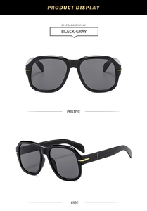 Detail of square oversized black sunglasses featuring gold arrow accents on the side temples