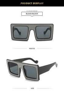 Detail view of square oversized sunglasses with silver glitter frame and black lenses
