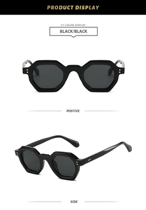Detail of black polygonal sunglasses featuring signature gold stud accents and frame texture
