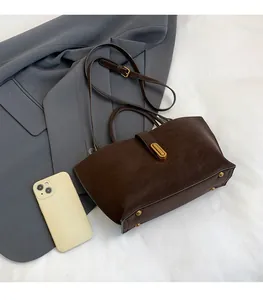 Detailed view of brown faux leather handbag with gold twist lock and metal bottom studs