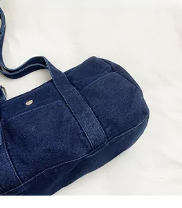 Detailed close-up of dark blue denim canvas bag texture with metal buckle and shoulder strap