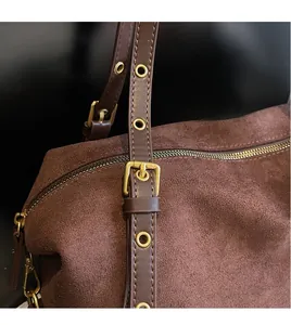 Detail of dark brown suede shoulder bag showing adjustable strap with gold metal eyelets