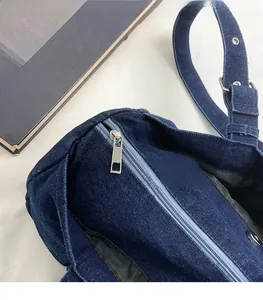Close-up of silver metal zipper and hardware details on blue denim canvas handbag