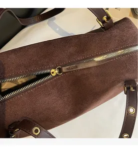 Detailed close-up of the smooth gold-toned zipper on a brown matte suede shoulder bag