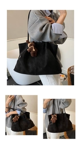 Close-up of black suede tote bag featuring a cute brown teddy bear plush charm