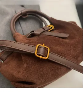 Dettaglio borsa in camoscio marrone con tracolla regolabile e fibbia in oro vintage