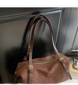 Detail of soft brown suede shoulder bag with durable leather strap and gold buckle