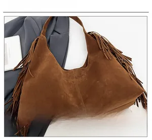 Detail of dark brown matte suede shoulder bag with retro fringe and soft texture