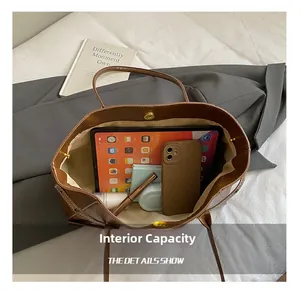 Vue de dessus du cabas en cuir marron montrant l'intérieur spacieux et accessoires