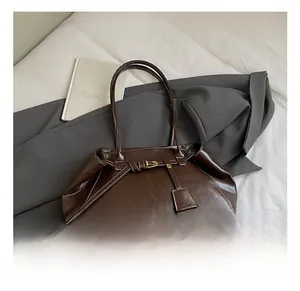 Détail du sac à bandoulière en cuir marron foncé avec surpiqûres blanches et boucle