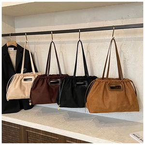 Détail de sacs cabas en daim en quatre couleurs avec cordon de serrage et breloque