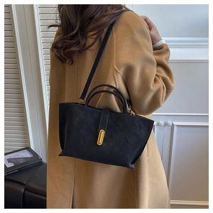 Detailed view of matte black trapezoid bag with gold buckle and stylish long shoulder strap