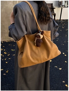 Outdoor shot showing back view of large camel tote bag with cute bear charm on shoulder