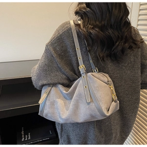 Close-up of grey frosted leather shoulder bag with adjustable strap and metal eyelets
