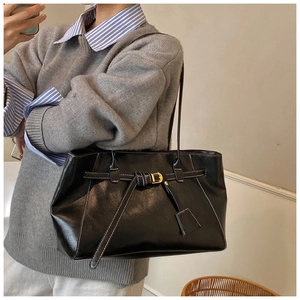 Gros plan sur un sac cabas noir avec surpiqûres blanches et boucle décorative
