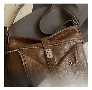 Detail view of lychee-textured dark brown leather bag with silver metal lock and zippers
