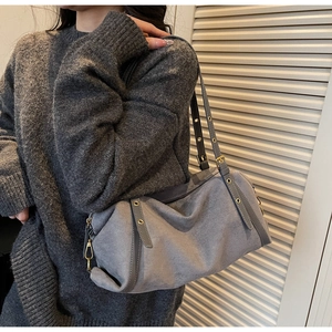 Detail of grey suede shoulder bag with long strap accents and gold hardware on model