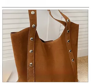 Detail of silver metallic studs on a dark brown suede tote bag for women's daily commute