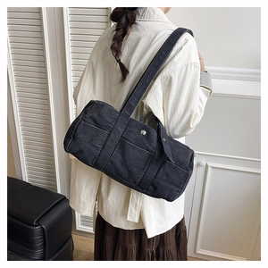 Black denim tote bag with decorative stitching and metal buckle shown on shoulder