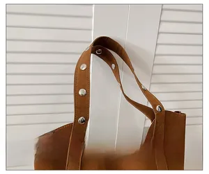 Macro detail of brown suede tote bag shoulder strap with silver round metal rivets