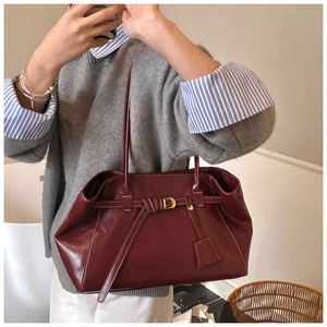 Détail du sac cabas en cuir bordeaux avec surpiqûres blanches et boucle dorée chic