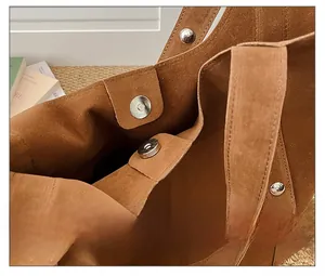 Close-up of magnetic snap closure and silver rivet details on brown suede tote bag