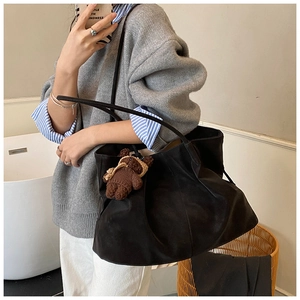 Detail of black matte tote bag with teddy bear pendant and elegant shoulder strap design