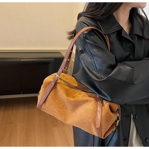 Detail of adjustable leather strap with gold metal buckle on a suede shoulder bag