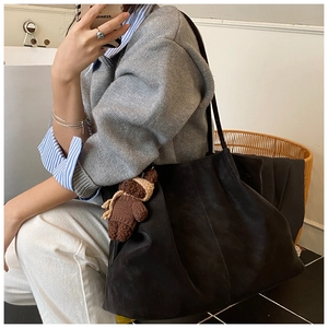 Close-up of black matte suede tote bag featuring a cute brown knitted bear charm