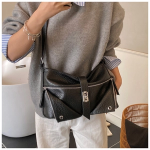 Detailed view of textured black faux leather bag with silver zippers and metal hardware