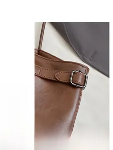 Detail shot of brown leather tote bag showing neat stitching and silver metal buckle