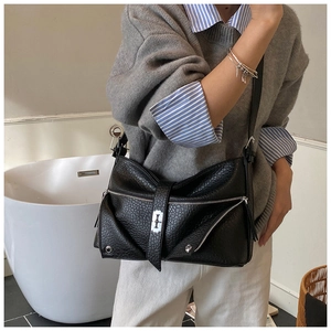 Detail of black pebbled leather tote bag with silver zippers and industrial cross buckle