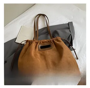 Détail du sac cabas en daim marron avec poignée ovale et breloque en forme de cœur