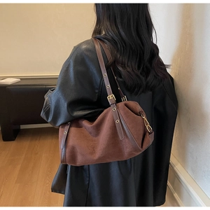 Deep brown oversized suede shoulder bag with gold hardware shown in casual use