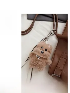 Close-up of brown plush dog charm with TOP DOG bone tag attached to a tote bag