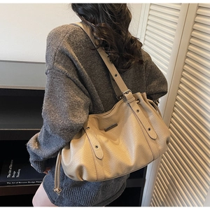 Detail of beige lychee leather tote with adjustable strap and metallic logo plate