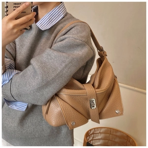 Close-up of camel leather shoulder bag with moto-jacket zipper and metal rivet details