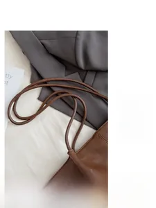 Detailed close-up of dark caramel brown leather straps on a large commuter tote bag