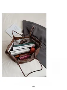 Brown tote bag showing spacious interior with books and umbrella on a soft white cloth