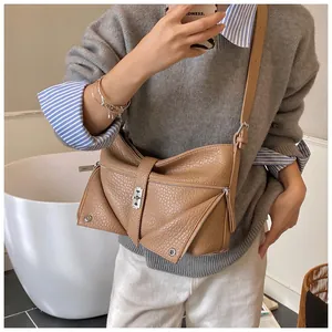 Detailed view of caramel faux leather bag with bow design and silver metal clasp