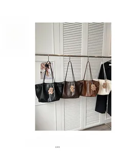 Detail view of four large tote bags with bear charms in black, brown, and cream colors