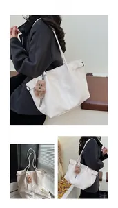 Detail of white leather tote bag with leather texture and plush bear charm