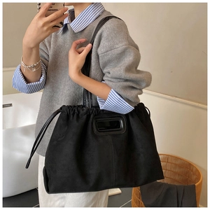 Détail du sac cabas en daim noir avec poignée rectangulaire découpée et cordon de serrage