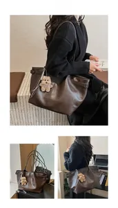 Detail of deep brown large tote bag with adjustable side straps and plush bear charm