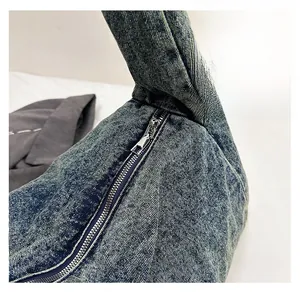 Detail of smooth metal zipper and washed denim fabric texture on a retro shoulder bag