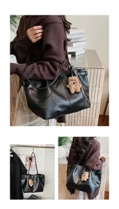 Detail of a large black tote bag with vintage texture and a brown plush bear charm