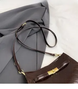 Close-up of brown quilted faux leather handbag with golden rectangular turn-lock