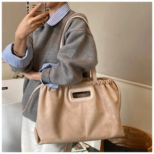 Détail d'un grand sac cabas en daim beige avec cordon de serrage et poignée découpée