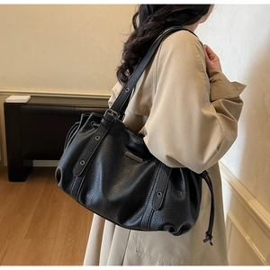 Detail of black lychee grain leather tote bag with silver hardware and drawstring
